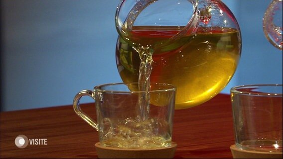 Aus einer gläsernen Kanne wird gelbe Flüssigkeit in ein Glas gegossen. © Screenshot 